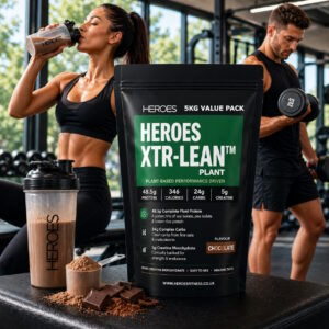 Bright gym scene featuring Heroes XTR-LEAN Plant Protein chocolate 5kg value bag in the foreground, with a fit woman drinking a chocolate shake and a muscular man lifting weights in the background